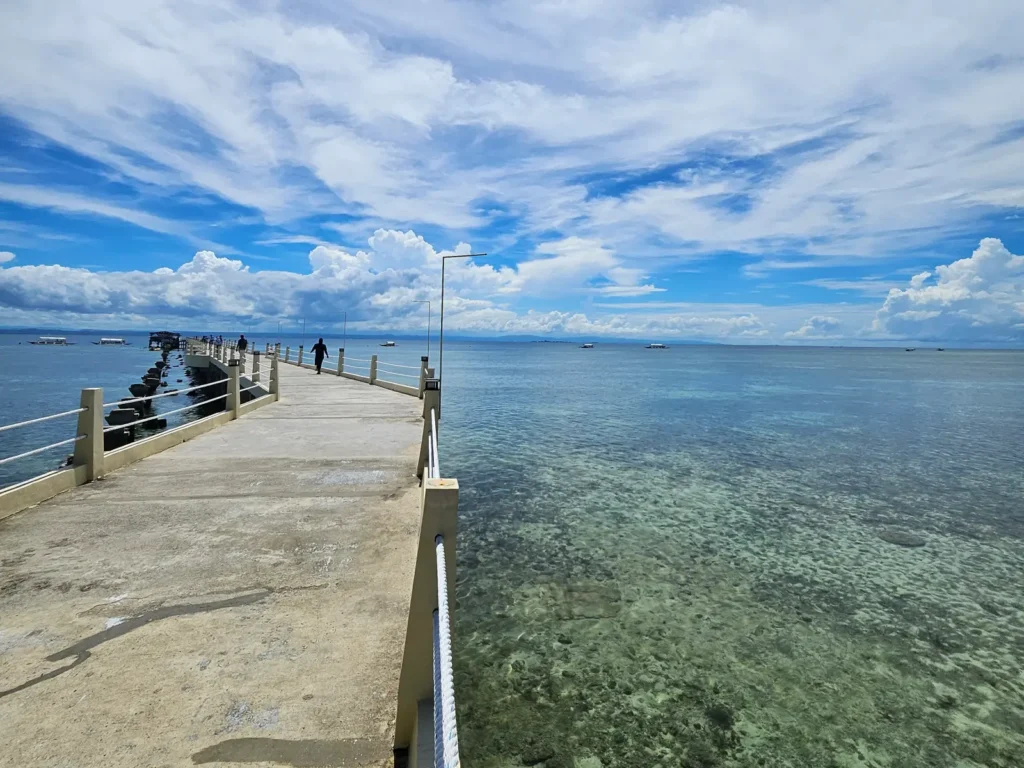 Scenic view of the long pier at Nalusuan Island Marine Park under a blue sky