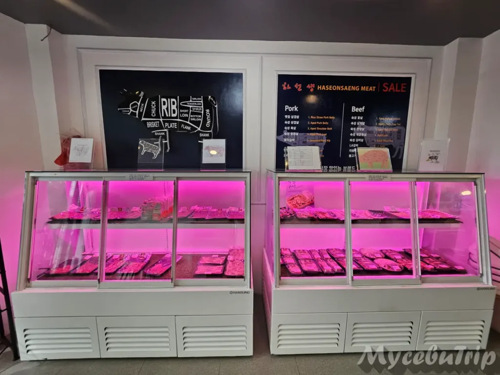 Close-up of the refrigerated meat display cases showing various cuts of fresh pork and beef.
