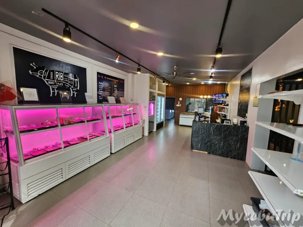 Wide shot of the restaurant's entrance area showing the meat shop counter and the reception desk.