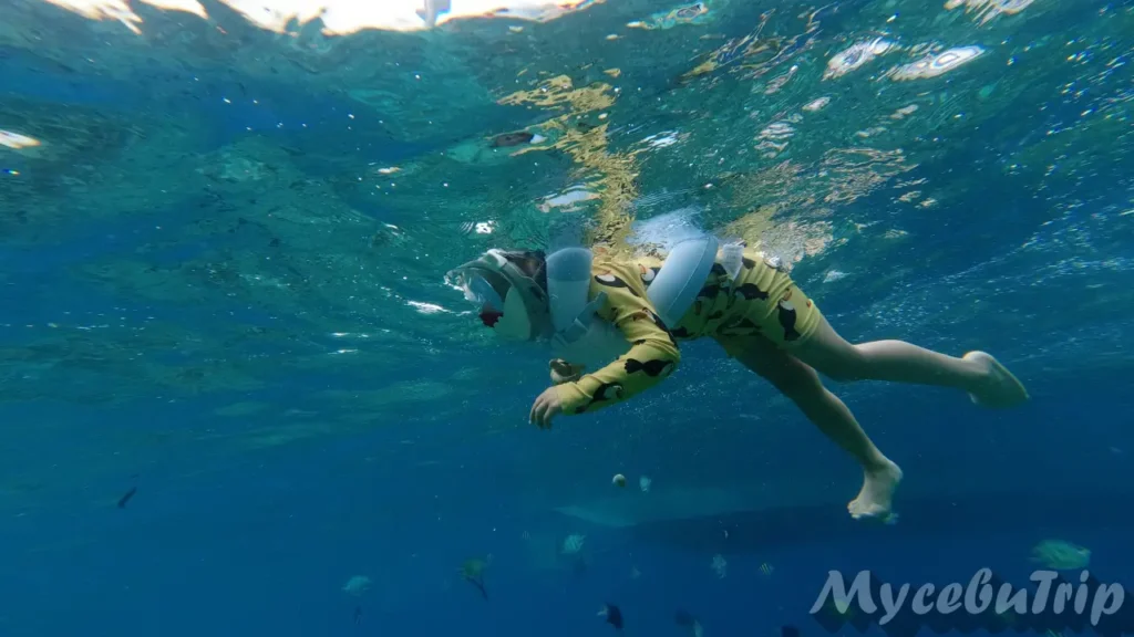Side view of a child snorkeling comfortably in the deep and clear ocean at Hilutungan.