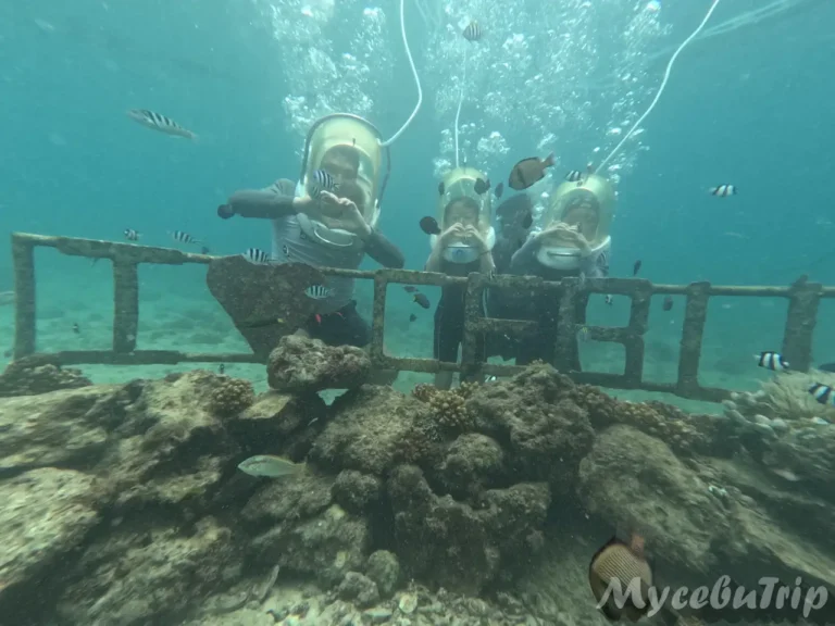 Couple making a heart shape with their hands at the underwater CEBU photo zone