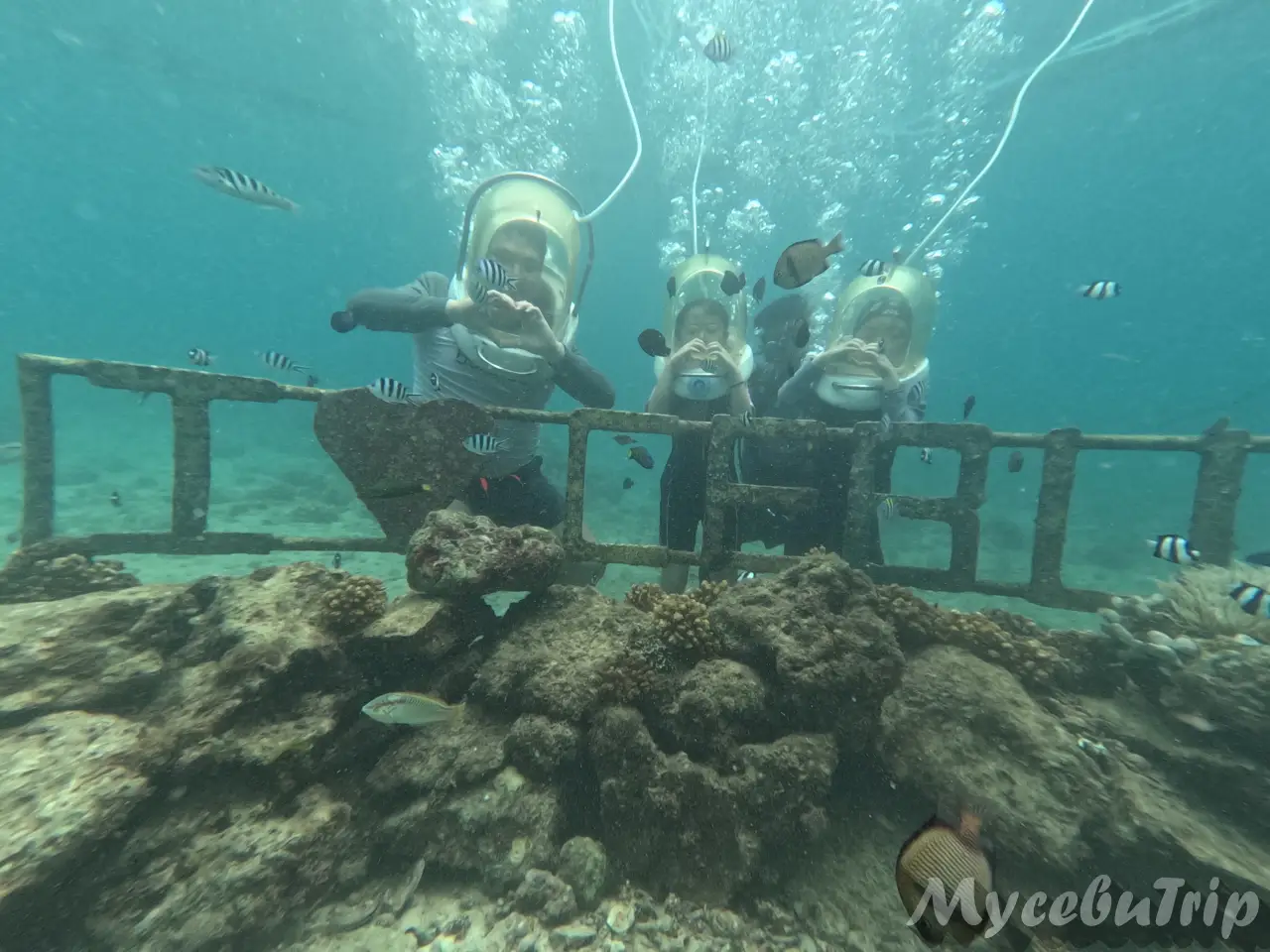 Couple making a heart shape with their hands at the underwater CEBU photo zone