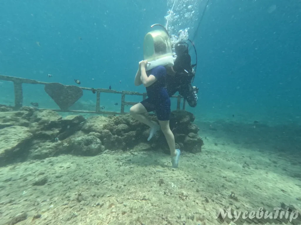 Solo traveler posing next to the large underwater CEBU landmark