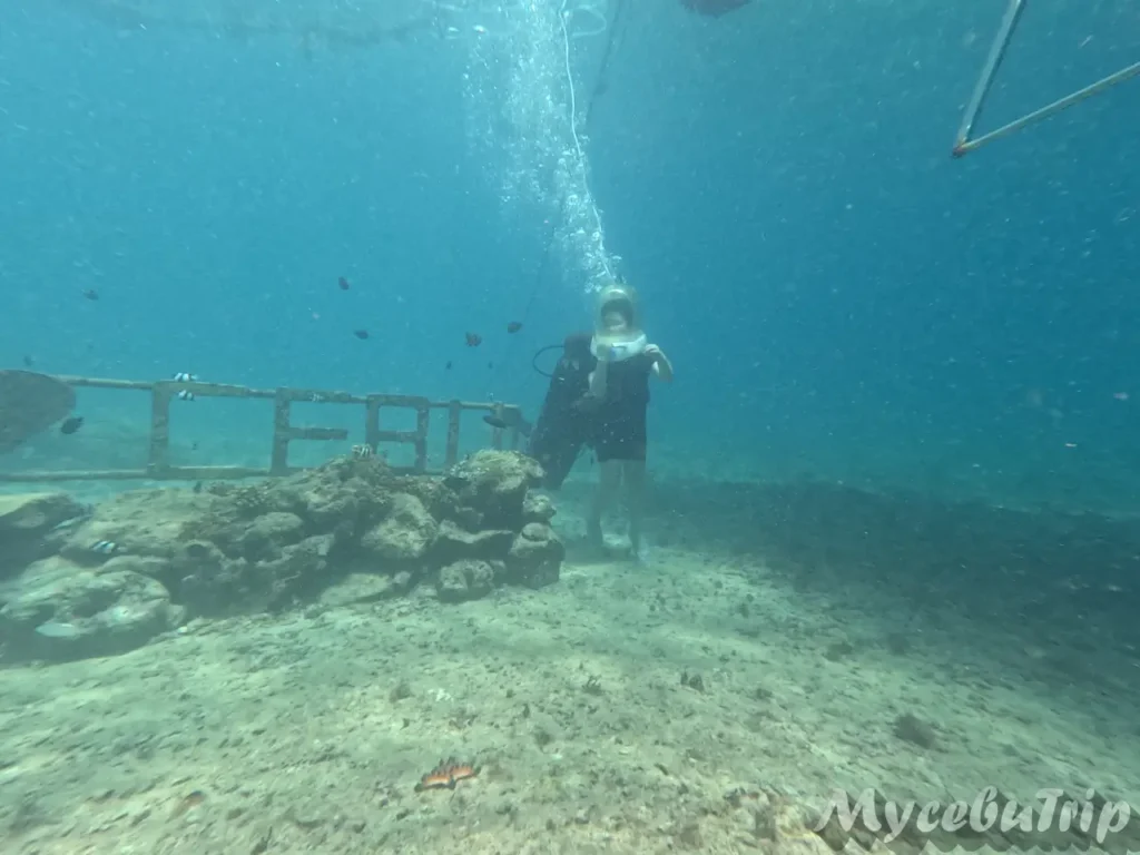 Tourist walking freely on the ocean floor wearing a diving helmet